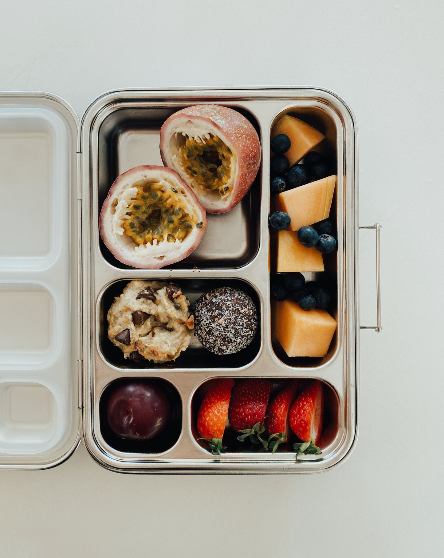 Stainless steel bento box with 5 compartments. Sustainable, eco-friendly, and zero plastic lunchbox alternative.  Fruit salad and fresh baked and raw treats.